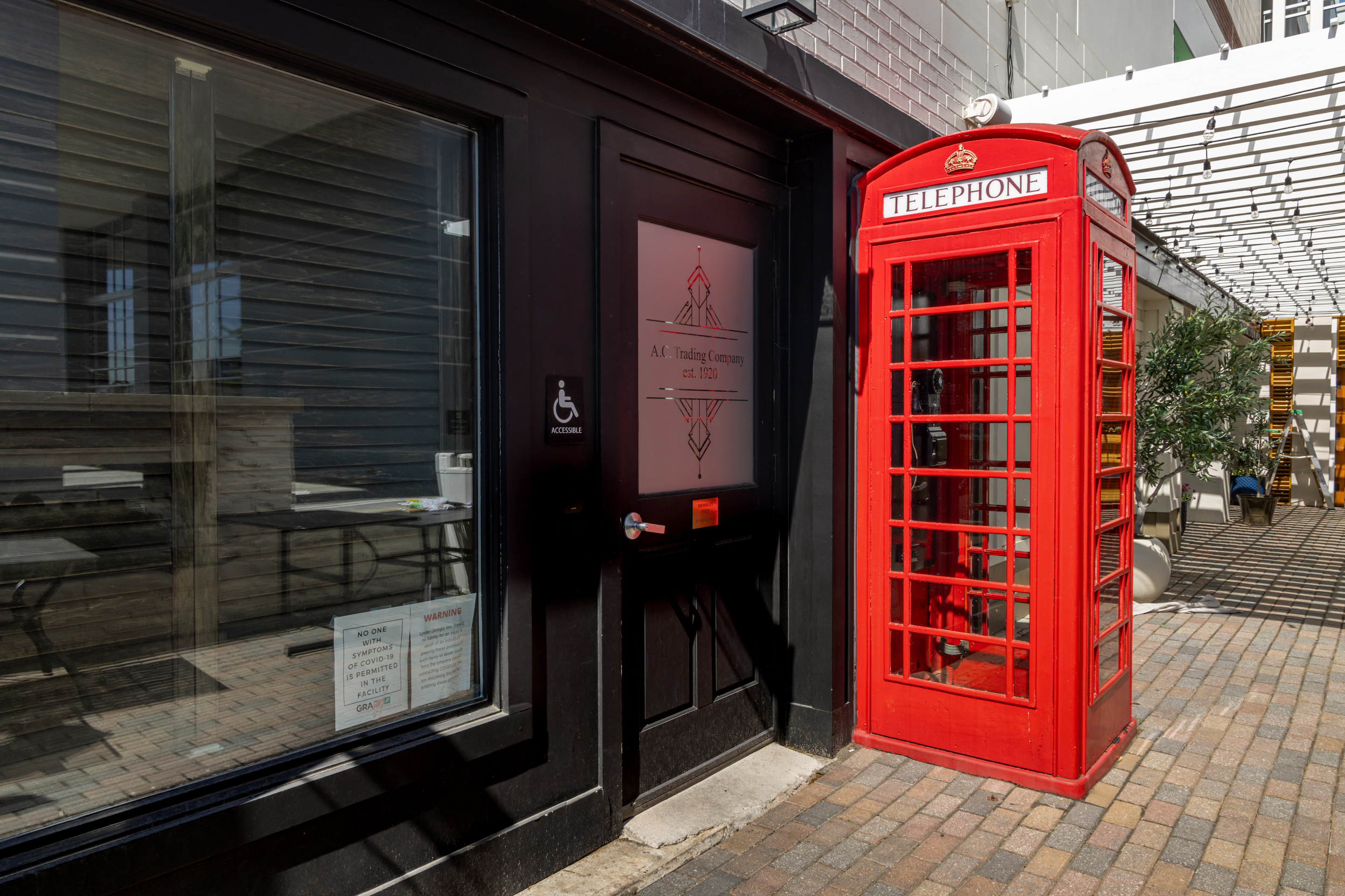 The red telephone booth outside Red Phone Booth, framed by the storefront and outdoor walkway